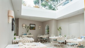 Un comedor luminoso y espacioso con mobiliario blanco y un techo alto.