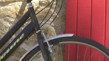Una bicicleta apoyada en una pared de piedra con una puerta roja.
