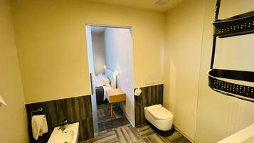 Een kleine hotelbadkamer met een wc, wastafel en bidet.