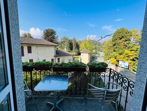 A balcony with a table and chairs, overlooking a residential area with houses and a mosque. - Hotel Santa Caterina (Orta San Giulio)