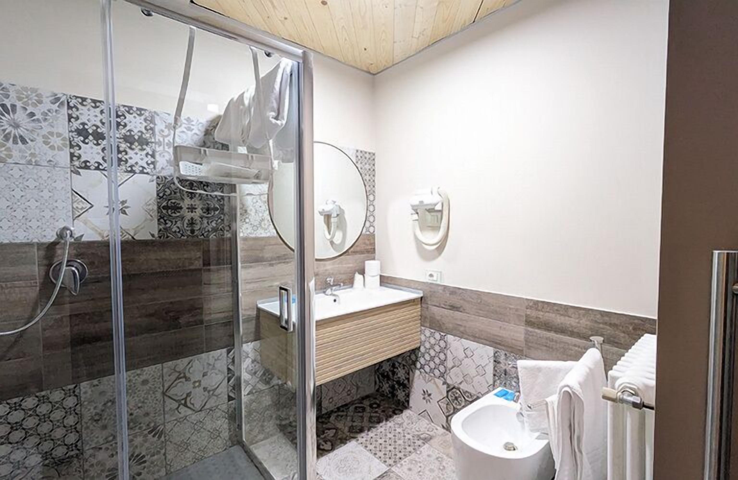 Un baño moderno con cabina de ducha de vidrio, tocador de madera y un bidé.