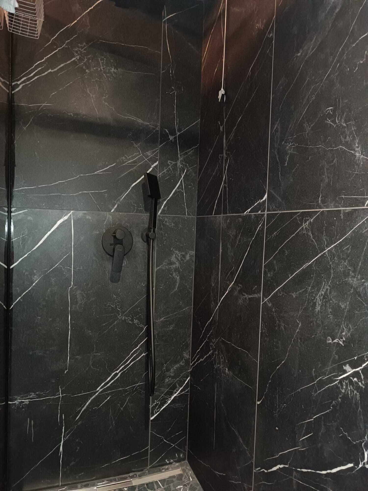 Eine Dusche mit Handbrause und Armaturen an der Wand.
