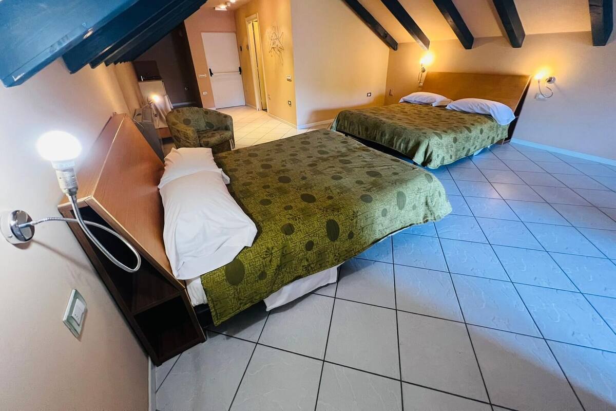 A hotel room with two beds, a small seating area, and a visible bathroom.