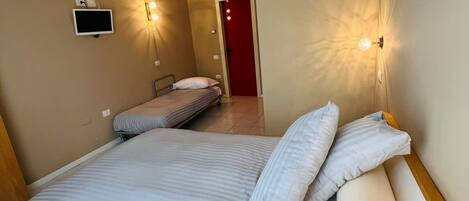 A bedroom with a bed, a television, and two wall-mounted lights.