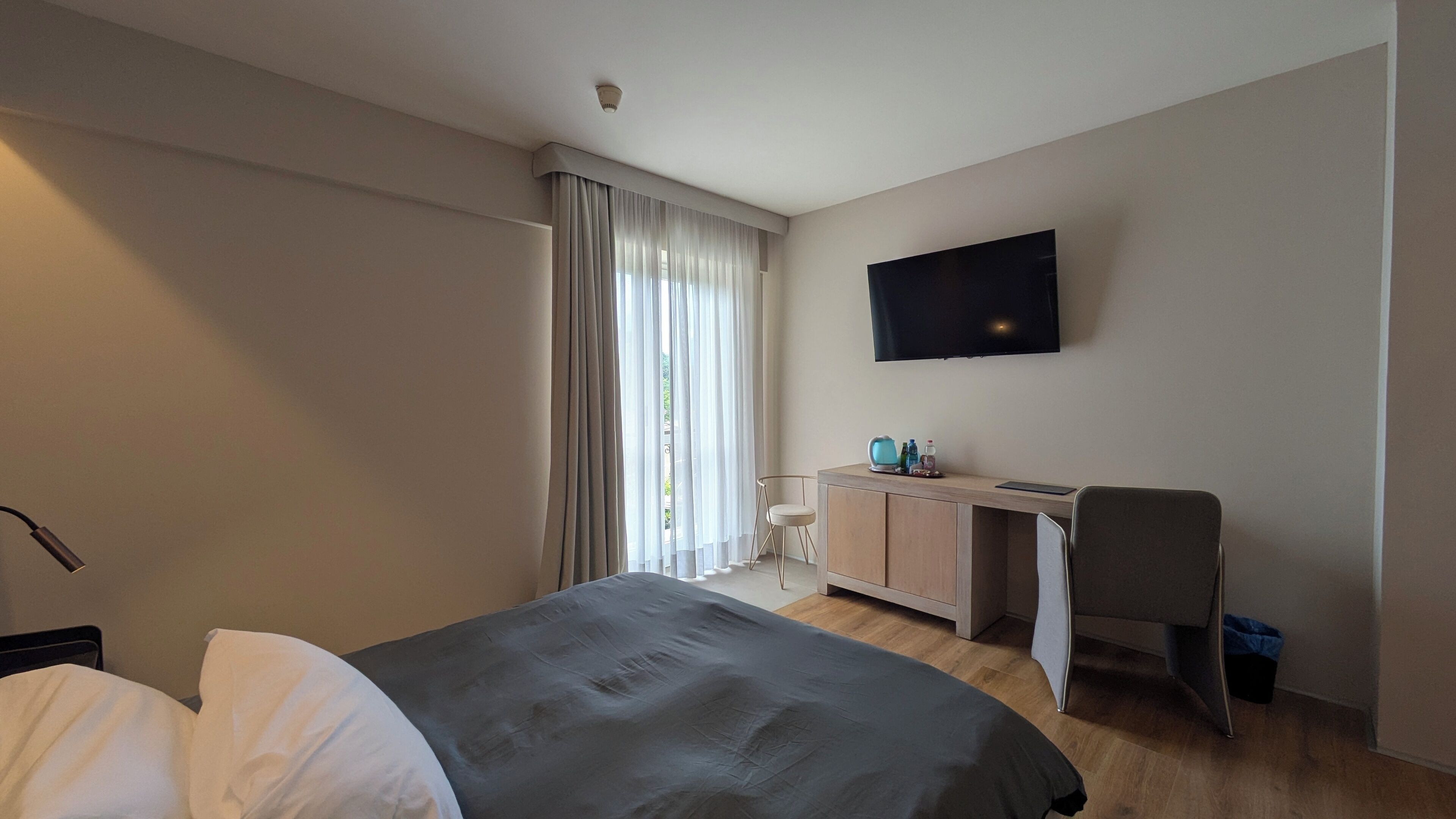Una habitación de hotel moderna con una cama, un escritorio, una silla y un televisor fijado a la pared.
