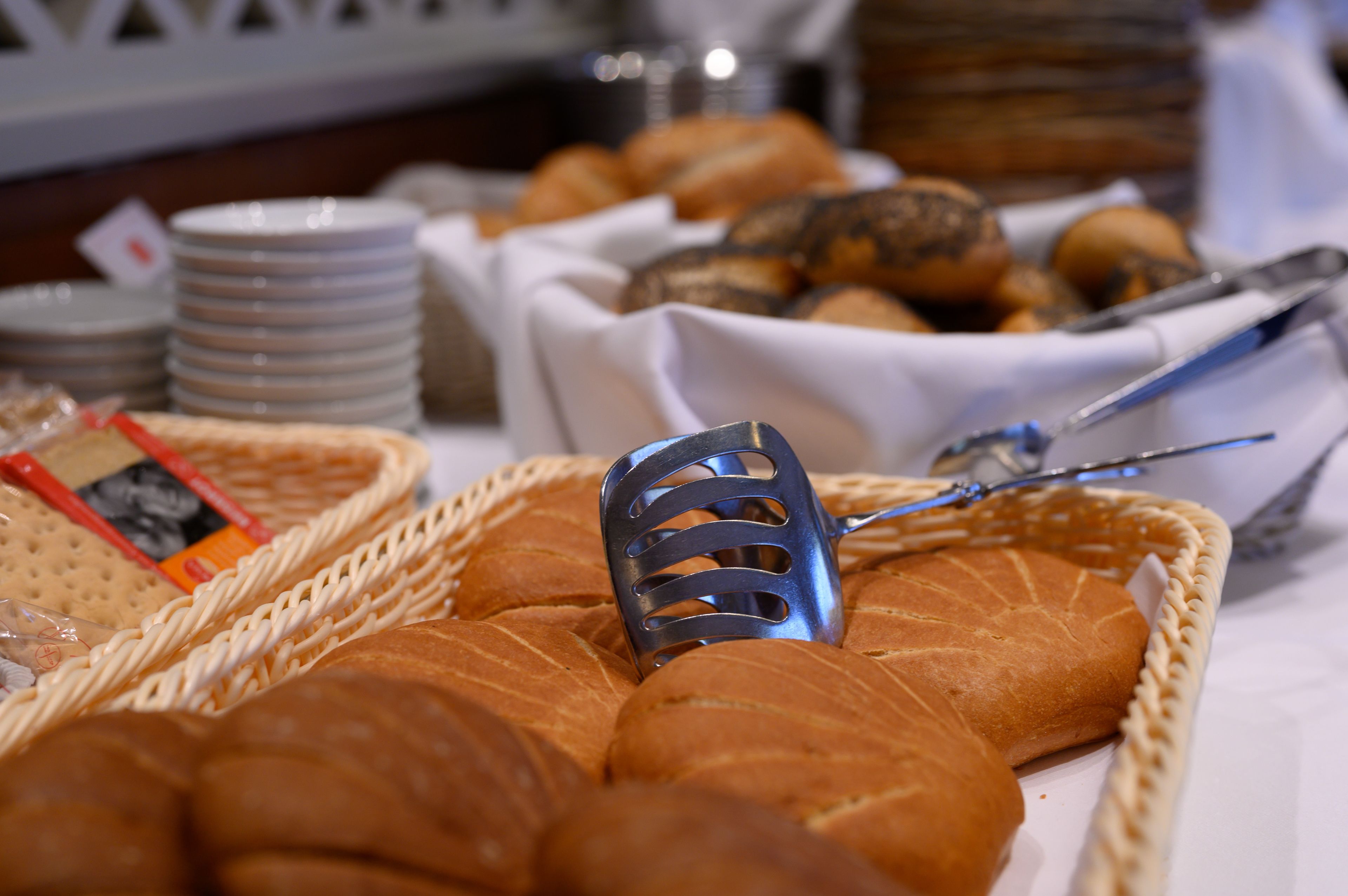 Een mand met broodjes en een groot brood op een tafel.