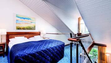 A bedroom with a large bed, a wooden headboard, a painting on the wall, and a staircase leading to an upper level.