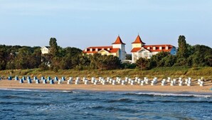 Un edificio costero con techos rojos, rodeado por una playa con barreras blancas.