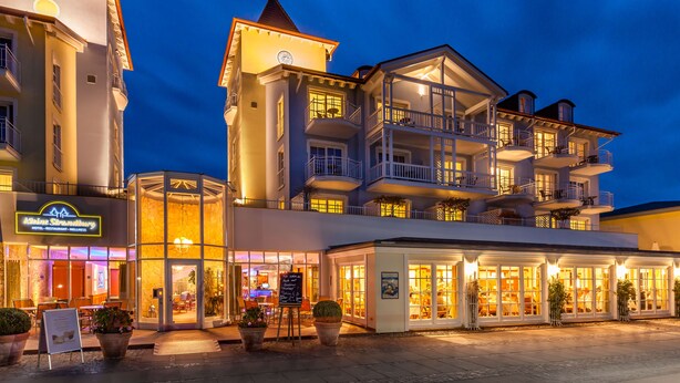 Un hotel con varios balcones, una torre destacada y una fachada bien iluminada.