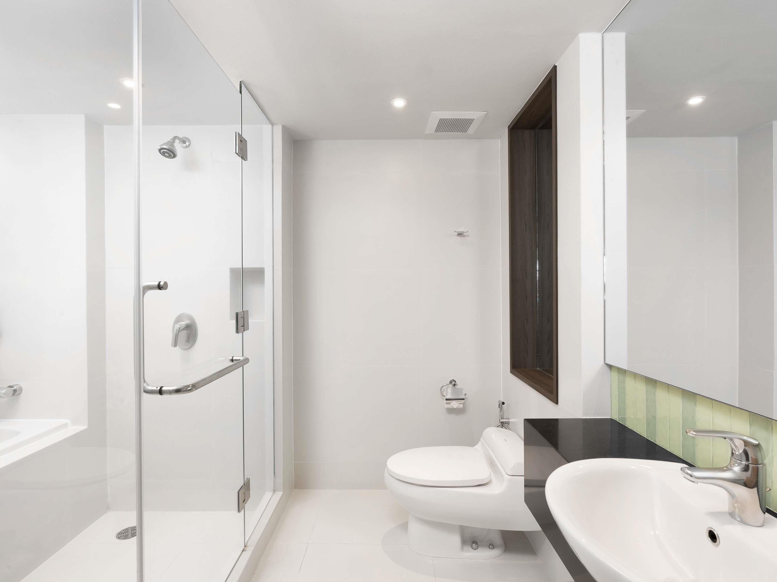 A modern bathroom with a glass-enclosed shower, a white toilet, and a sink with a dark countertop.