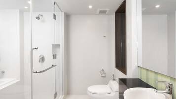 A modern bathroom with a glass-enclosed shower, a white toilet, and a sink with a dark countertop.