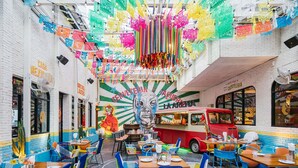 A vibrant restaurant with colorful decor, a mural, and a vintage car. - Novotel Living Bangkok Sukhumvit Legacy (Bangkok)