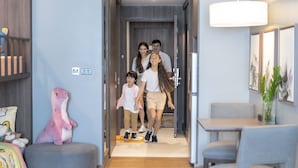 A family walking through a modern hallway with a dining area on the right.