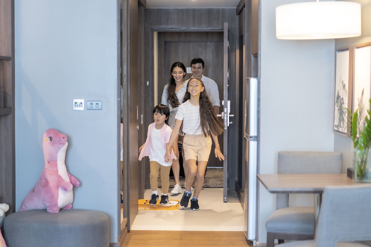 A family walking through a modern hallway with a dining area on the right.