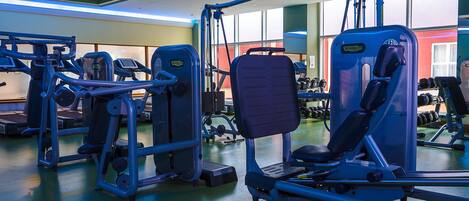 A gym with various exercise machines, a treadmill, and dumbbells.