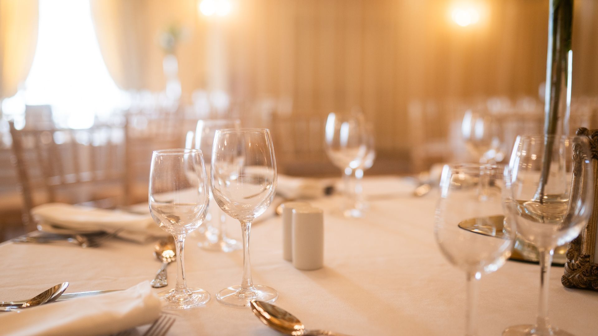 Mesa lista para comer con copas de vino, platos y cubiertos.