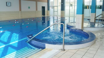 An indoor swimming pool with clear lane dividers, a hot tub, and a tiled floor.
