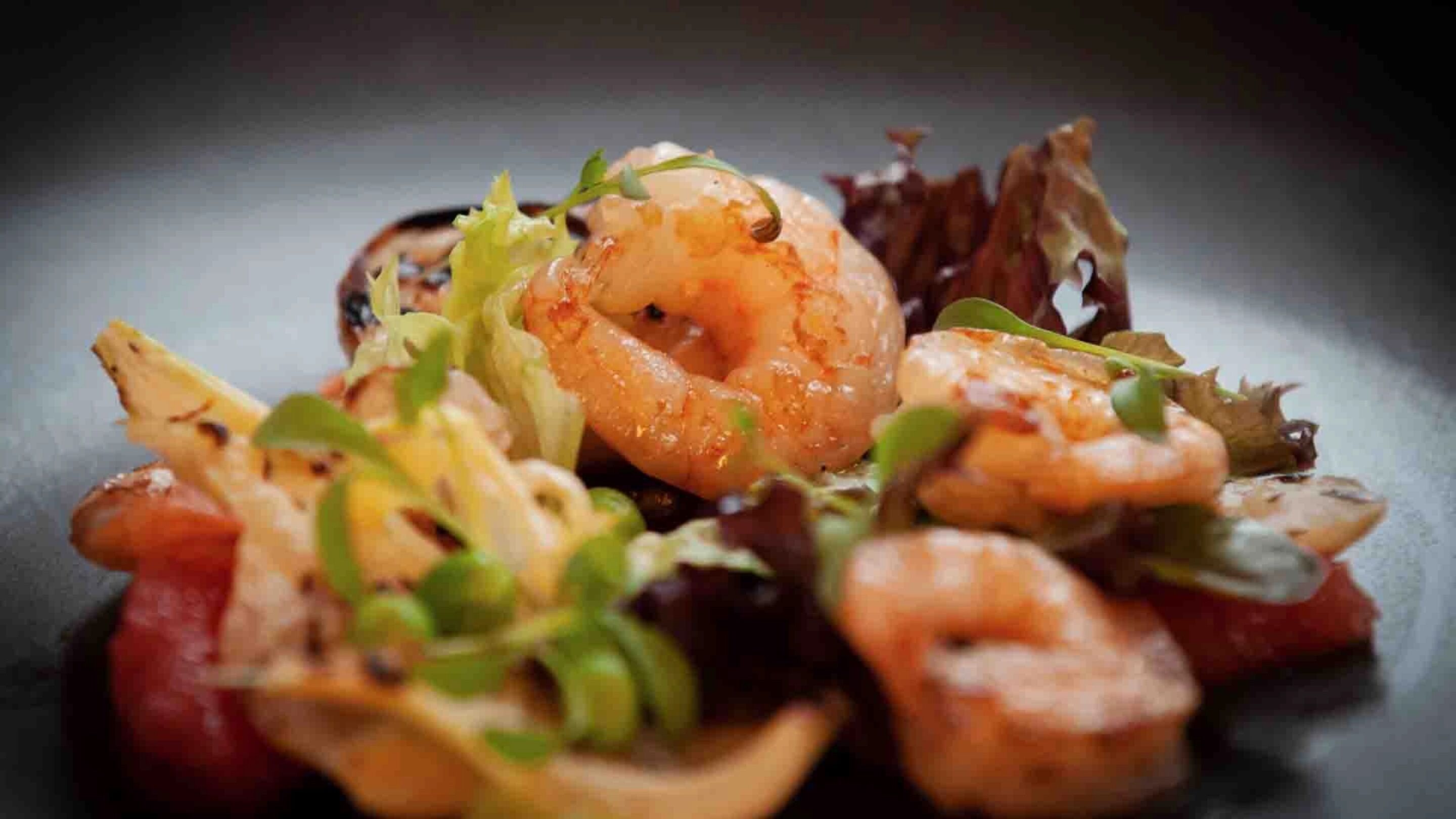 Une assiette de nourriture contenant des crevettes et des légumes verts.