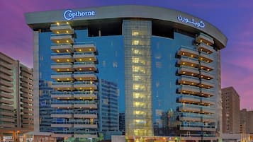 Un hôtel moderne à la façade incurvée, doté de nombreux balcons et d’une entrée imposante.