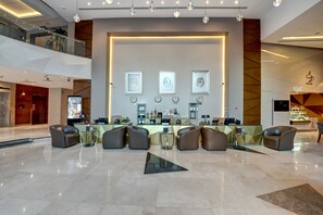 Eine moderne Lobby mit einer Rezeption, einer Sitzecke und einem großen Spiegel.