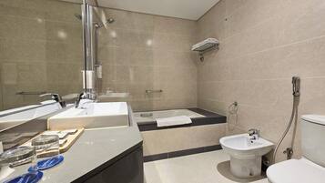 Een moderne badkamer met een grote spiegel, een badkuip, een toilet en een wastafel.