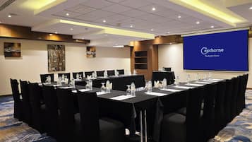 Ett konferensrum med ett långt bord, stolar, vattenflaskor och en skärm som visar texten ”Cophorne – det självklara valet när det gäller kvalitet”.