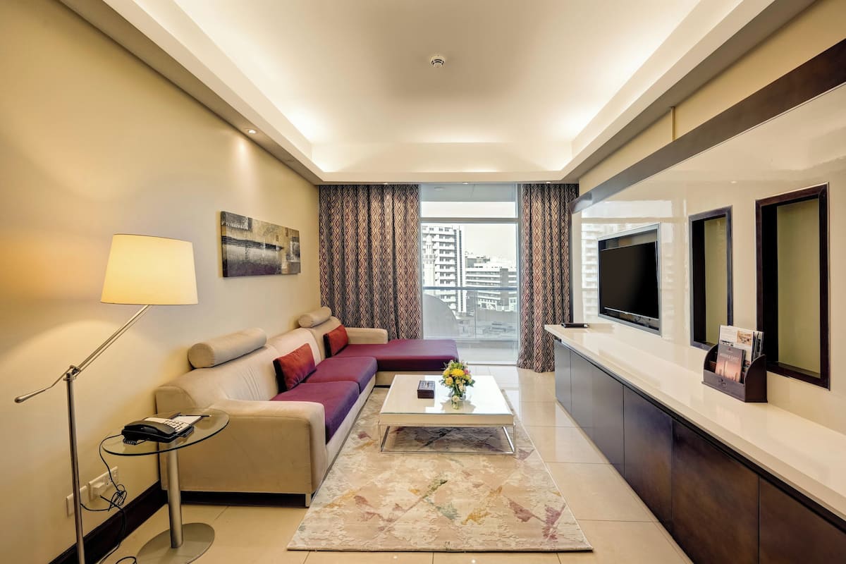 A modern living room with a sofa, coffee table, lamp, and TV.