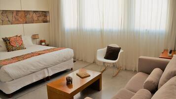 Una habitación de hotel con cama, sofá, mesa de centro, sillón y una pared decorada con piedra.