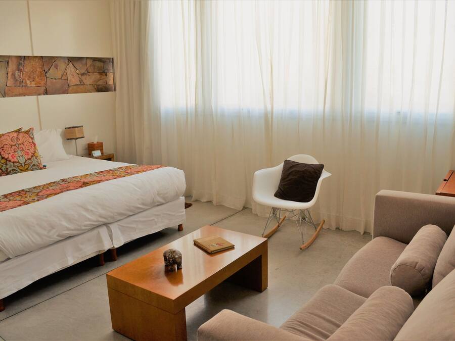 Una habitación de hotel con cama, sofá, mesa de centro, sillón y una pared decorada con piedra.