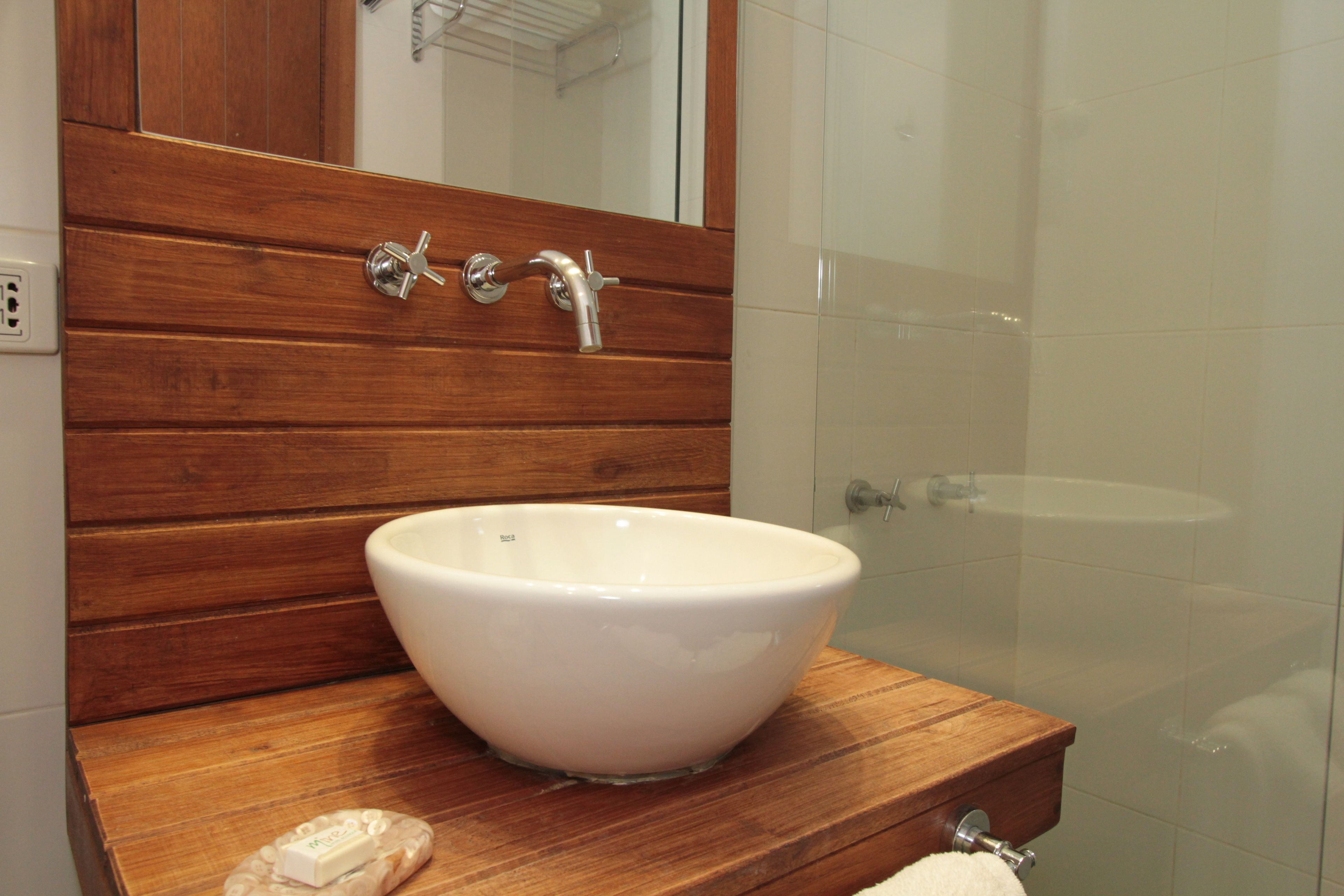 Un baño con tocador de madera, un lavabo blanco y un espejo encima.