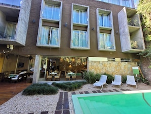 Un hotel con piscina, mobiliario exterior y fachada de piedra.