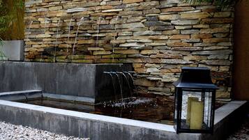 Un muro de piedra con una fuente de agua y un farol.