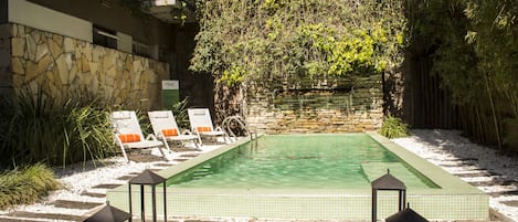 Una piscina al aire libre, sillones reclinables de piscina