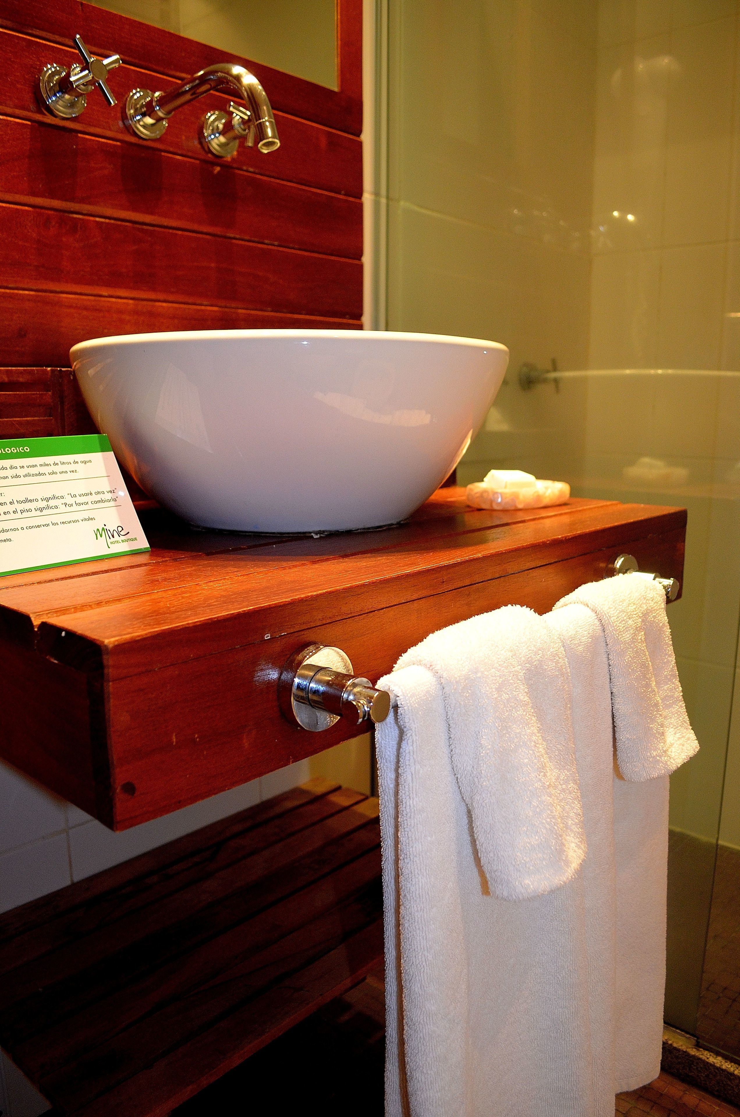 A bathroom with a wooden vanity, a white sink, and a glass shower enclosure.