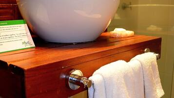 A bathroom with a wooden vanity, a white sink, and a glass shower enclosure.