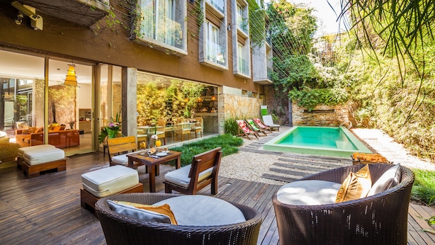 Un espacio exterior moderno con piscina, terraza de madera y mobiliario para exteriores.