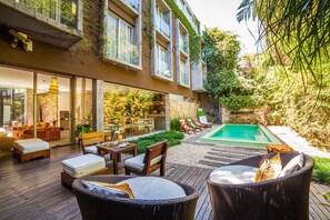 Un espacio exterior moderno con piscina, terraza de madera y mobiliario para exteriores.