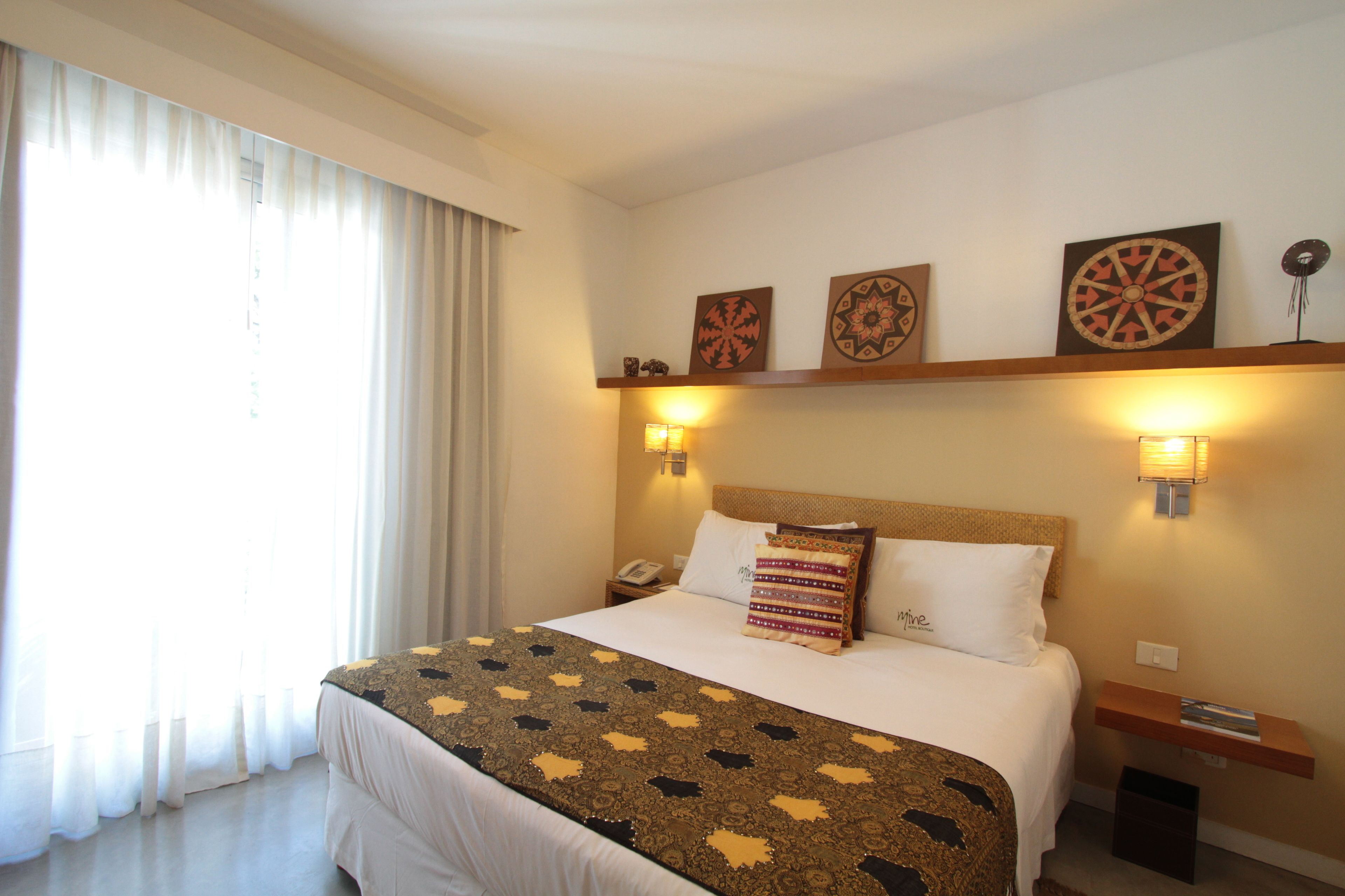 Una habitación de hotel con una cama grande, una mesita de noche y una repisa en la pared con objetos decorativos.