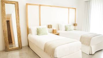 Quarto de hotel com duas camas, um espelho grande e uma cabeceira de madeira.