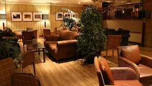 A spacious living area with a high ceiling, ceiling fans, and a large potted plant.