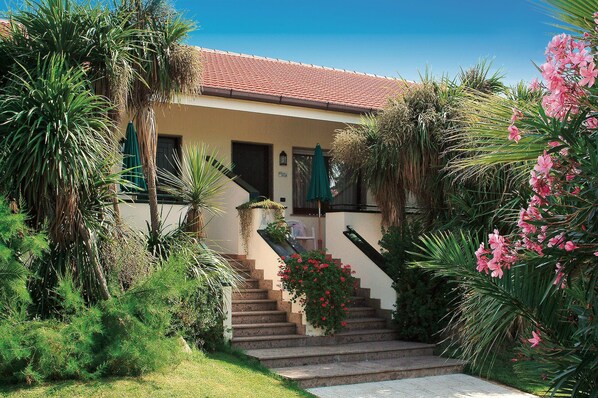 A house with a red-tiled roof, a staircase leading to a door, and lush greenery around. - Oleandri Resort (Capaccio-Paestum)