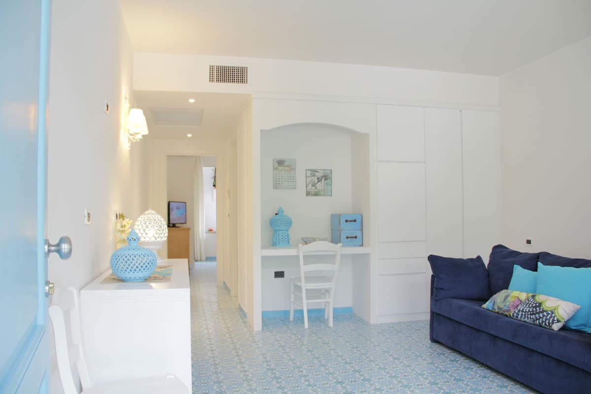 A room with a white desk, a blue sofa, and a chair.