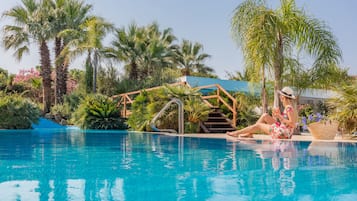 Una piscina al aire libre, sombrillas, sillones reclinables de piscina