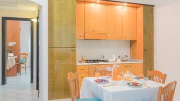 A modern kitchen with wooden cabinets, a dining table set for four, and a breakfast spread.