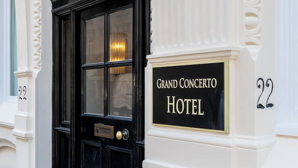 En svart dubbeldörr med en skylt ovanför som det står "Grand Concerto Hotel" på.