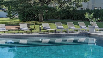 Una piscina al aire libre de temporada, sillones reclinables de piscina
