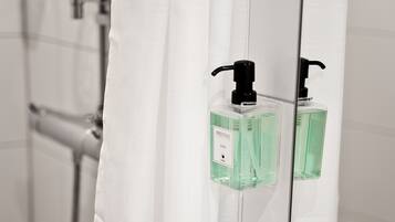 A bathroom with a white sink, a mirror, and a shower with a white curtain.