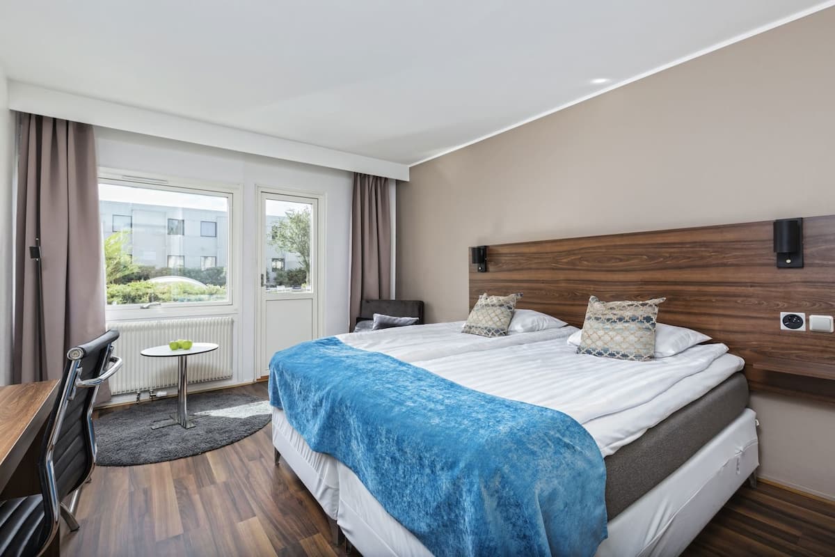 Une chambre d’hôtel avec un grand lit, un bureau et une vue sur l’extérieur.