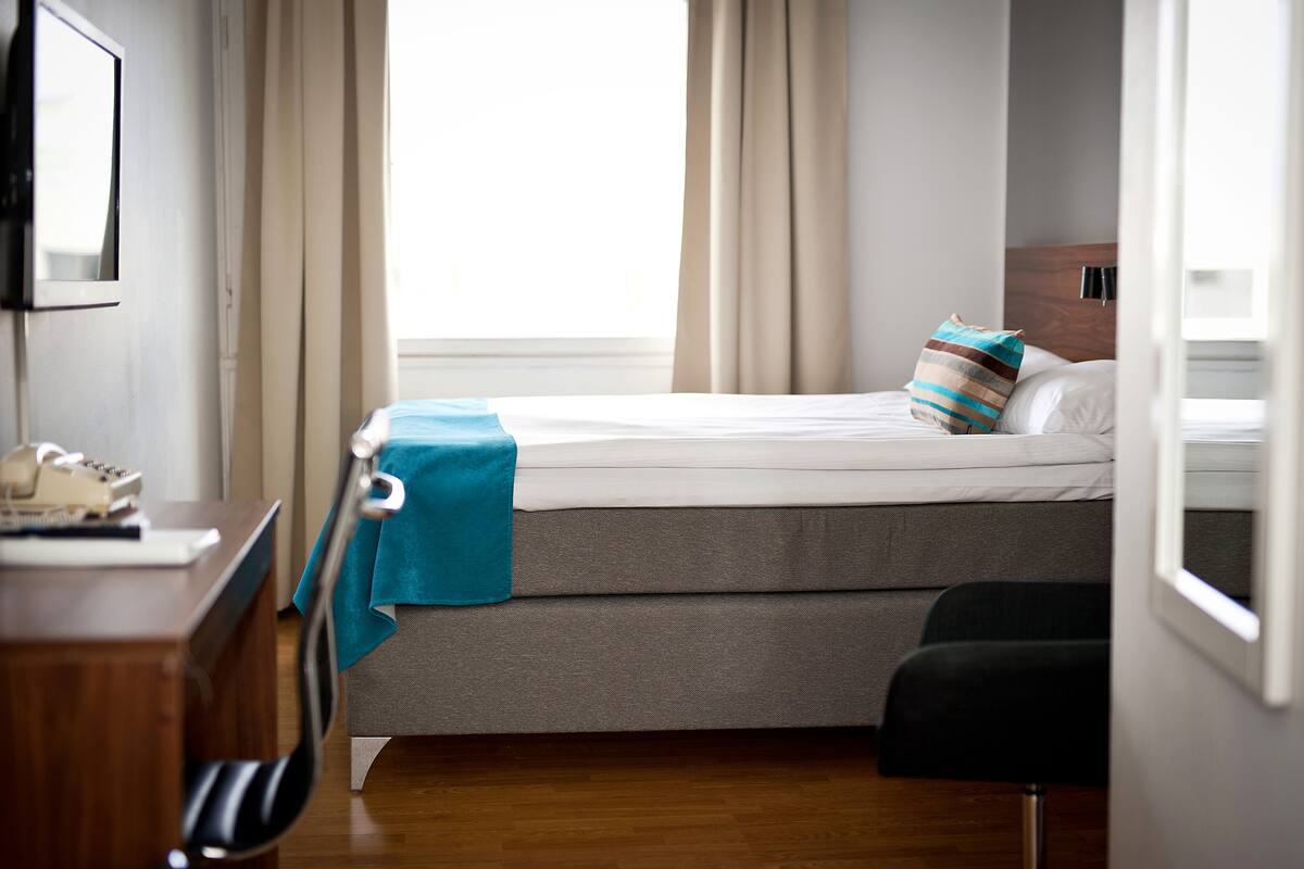 Une chambre d’hôtel avec un lit, un bureau avec un téléphone et une chaise.