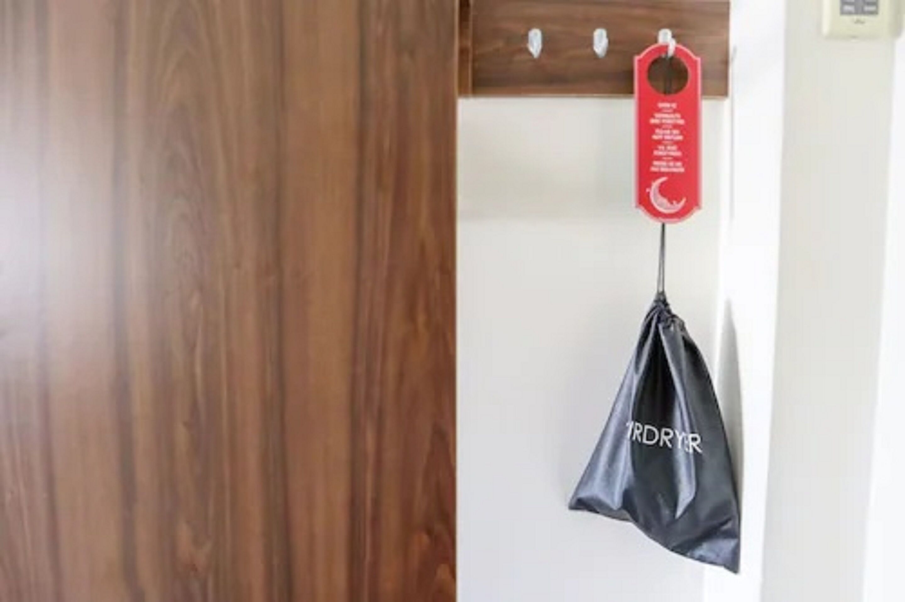 A wooden door with a black plastic bag hanging on a hook.